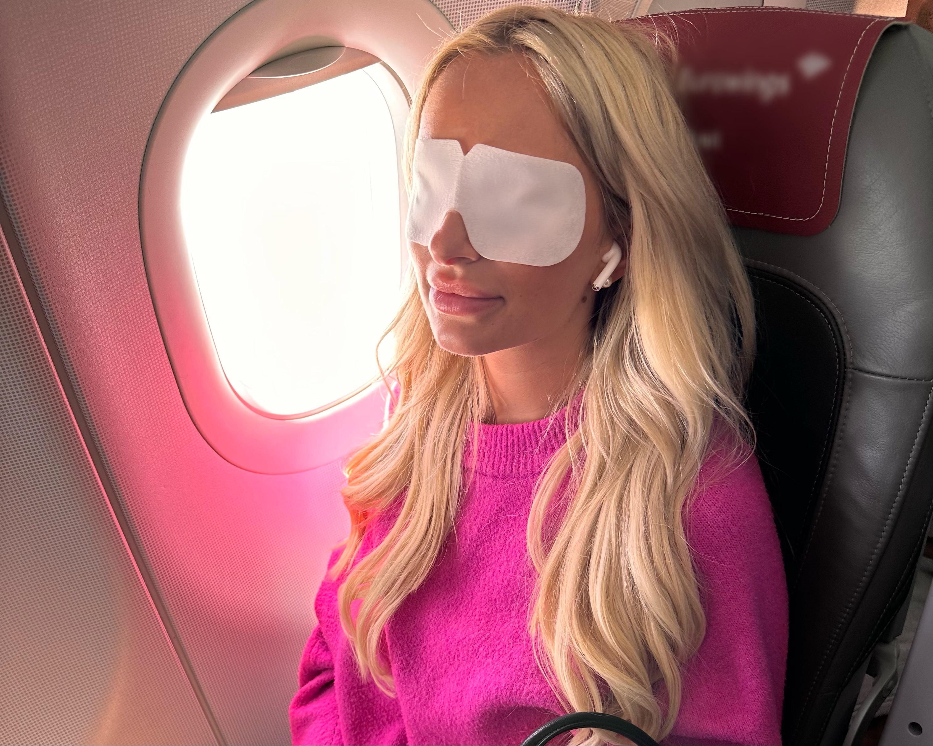 Realxees ist kühlende Augenmaske zum entspannen und gegen Augenschmerzen. Relaxees helfen Augenringe zu reduzieren. Eine Frau sitzt entspannt mit Relaxees auf den Augen im Flugzeug.